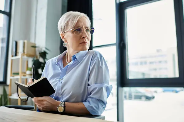 Middle-aged businesswoman with short hair at a table in her office — Stock Photo