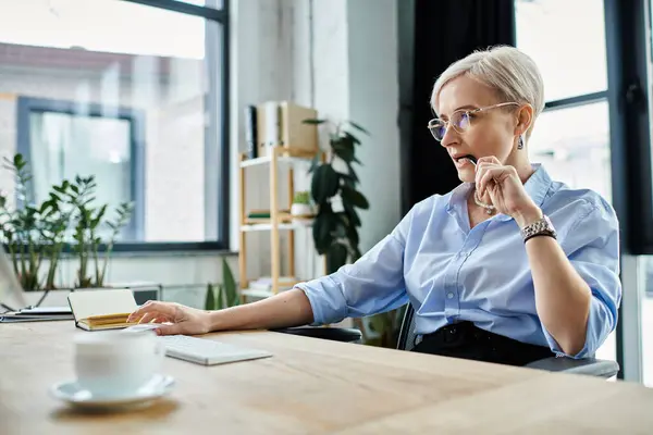 Una donna d'affari di mezza età con i capelli corti si concentra sul suo computer portatile — Stock Photo