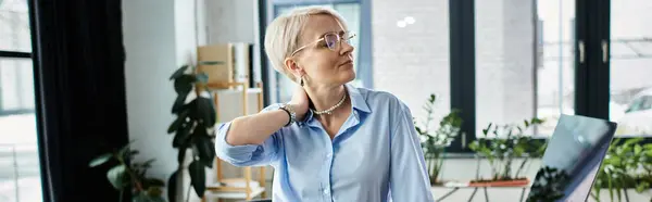 A middle-aged businesswoman with short hair works diligently on her laptop in an office during menopause. — Stock Photo