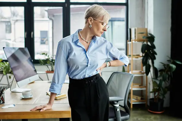 Empresaria de mediana edad con cabello corto sintiéndose mal durante la menopausia en un entorno de oficina. - foto de stock