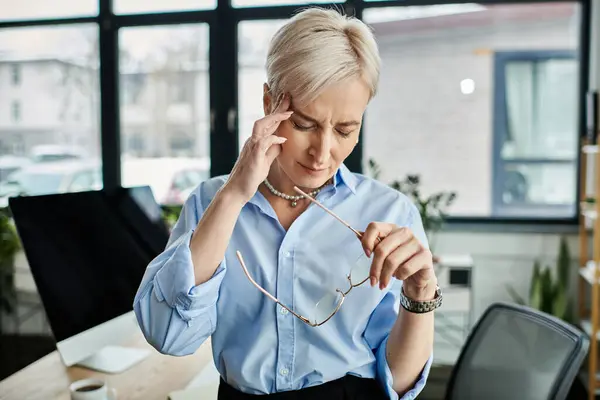 Middle-aged businesswoman in a blue shirt feeling unwell during menopause in the office. — Stock Photo
