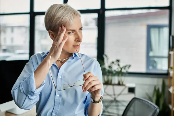 Geschäftsfrau mittleren Alters mit kurzen Haaren hält ruhig ihre Brille. — Stockfoto