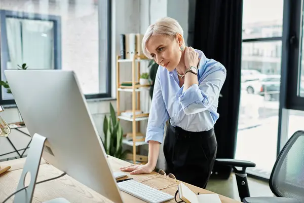 Geschäftsfrau mittleren Alters mit kurzen Haaren arbeitet während der Wechseljahre im Büro am Laptop. — Stockfoto