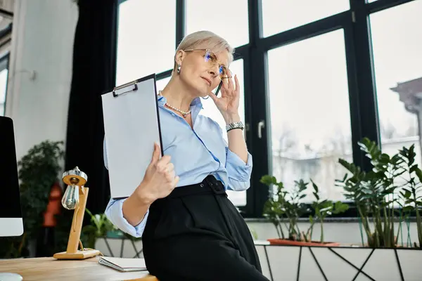 Empresária de meia-idade com cabelo curto sentado na mesa de escritório, sentando-se mal durante a menopausa — Fotografia de Stock
