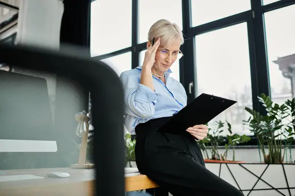 A middle aged businesswoman with short hair fully engrossed in her work while sitting at a desk — Stock Photo
