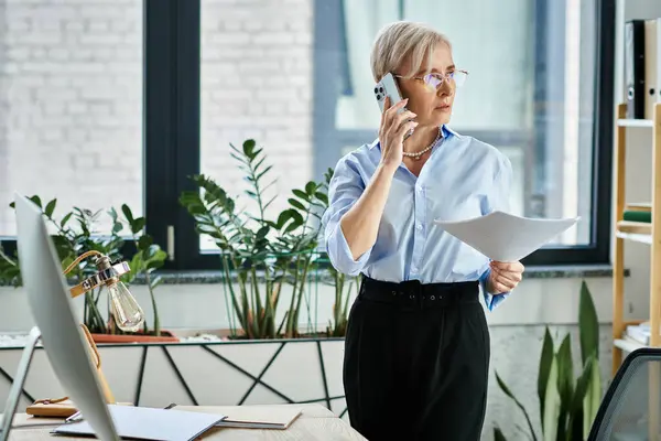 Eine Geschäftsfrau mittleren Alters mit kurzen Haaren spricht auf einem Handy in einem Büroumfeld. — Stockfoto