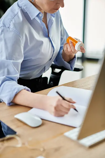 Eine Geschäftsfrau mittleren Alters mit kurzen Haaren schreibt in den Wechseljahren am Schreibtisch ihres Büros fleißig auf einen Zettel. — Stockfoto