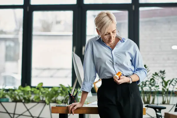 A middle-aged businesswoman with short hair stands confidently, holding pills from menopause. — Stock Photo