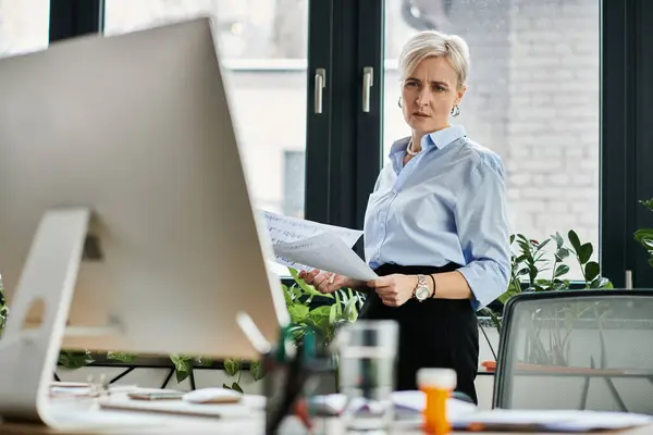 Une femme d'affaires d'âge moyen concentrée avec les cheveux courts travaille à son ordinateur dans un cadre de bureau. — Photo de stock