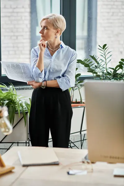 Empresaria de mediana edad con pelo corto trabajando en la computadora portátil en la oficina - foto de stock