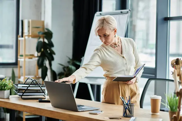 A middle-aged businesswoman with short hair, focused on work at her organized desk with a laptop. — Stock Photo