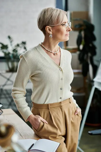 Eine Geschäftsfrau mittleren Alters mit kurzen Haaren steht vor einem Schreibtisch — Stockfoto