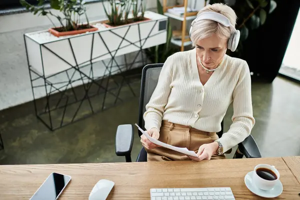 A middle-aged businesswoman with short hair works diligently at her desk in a modern office, focusing on her computer screen. — Stock Photo