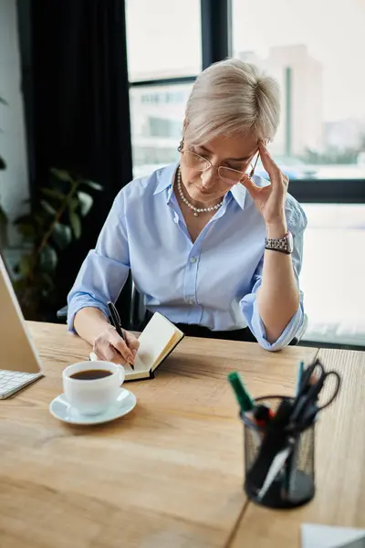 Middle-aged businesswoman with short hair at table in office — Stock Photo