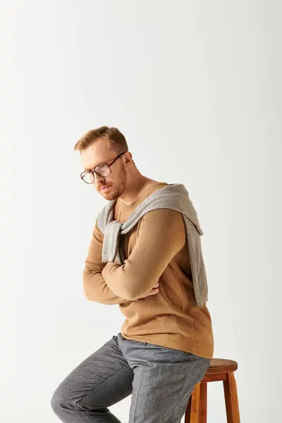 A stylishly attired man confidently perched atop a wooden stool. — Stock Photo