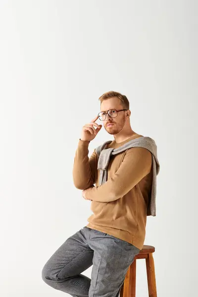 Handsome man in stylish attire posing actively on top of a wooden stool. — Stock Photo