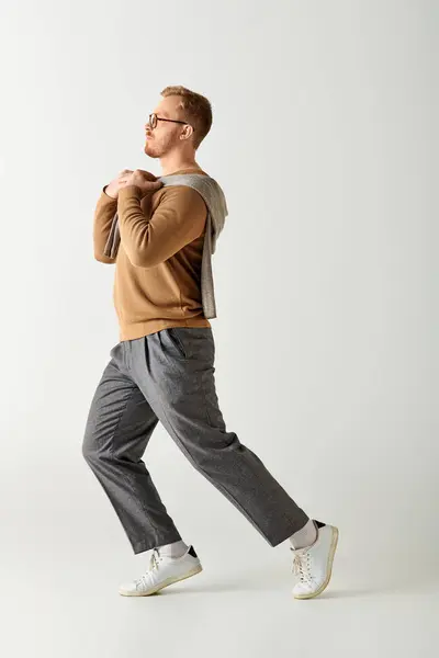 A stylish man wearing a brown sweater walks gracefully. — Stock Photo