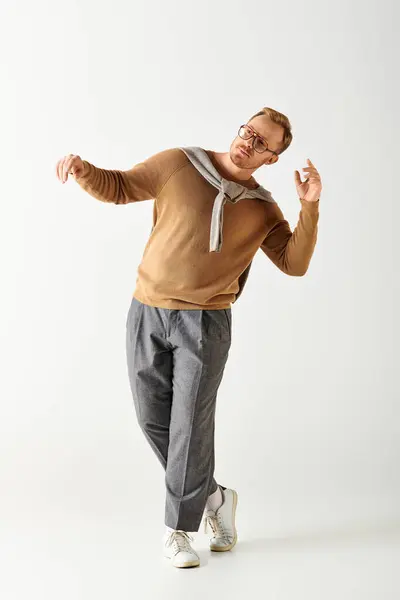 Handsome man actively posing in stylish brown shirt and grey pants. — Stock Photo