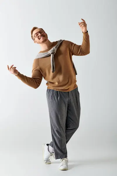 Handsome man in brown sweater and gray pants striking a pose. — Stock Photo