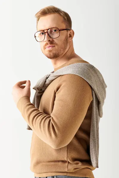 L'uomo bello in occhiali e un maglione posa con fiducia. — Foto stock