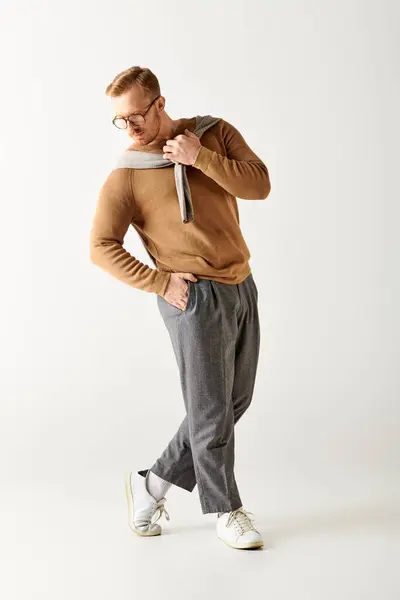 Handsome man in a brown sweater and grey pants striking a stylish pose. — Stock Photo