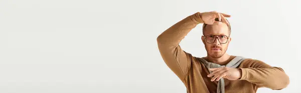 Stylish man in brown sweater posing with hands behind head. — Stock Photo
