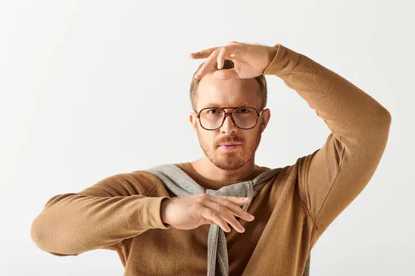 Handsome man poses actively in stylish brown sweater and glasses. — Stock Photo