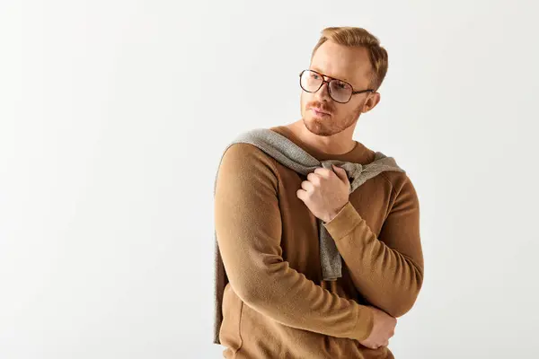 A man in glasses and a sweater strikes a stylish pose. — Stock Photo