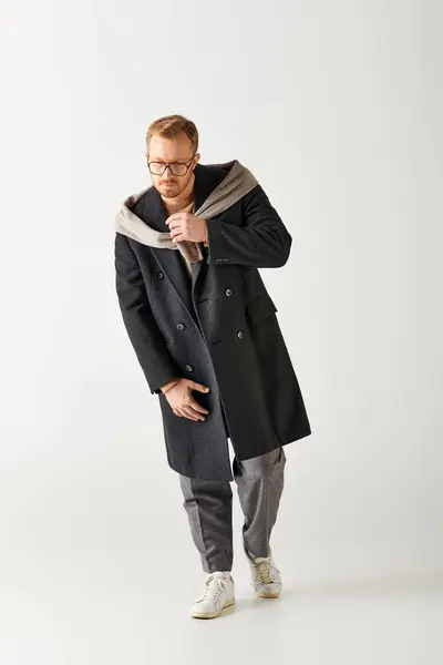 A dapper man in a coat and glasses confidently poses for a portrait. — Stock Photo