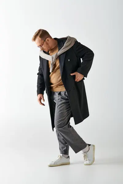 A stylishly dressed man confidently strides in a trench coat. — Stock Photo