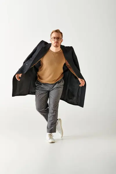 A handsome man actively posing in stylish brown shirt and black coat. — Stock Photo