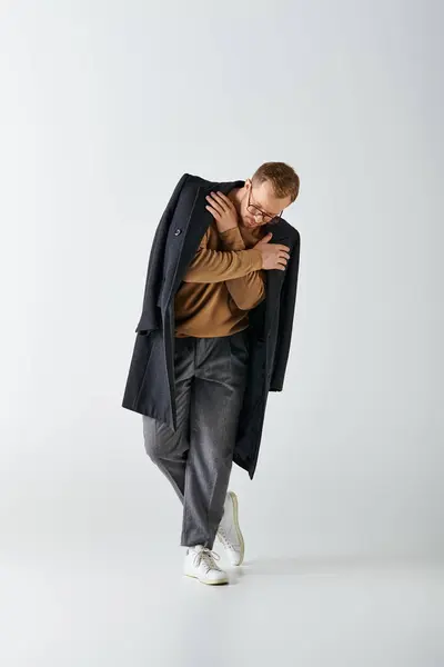 A stylish man poses confidently in a brown shirt and black coat. — Stock Photo