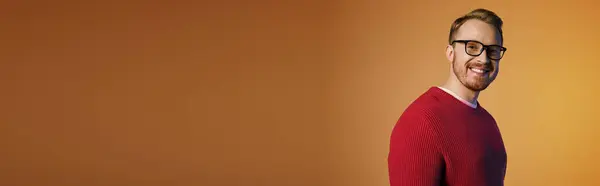 A handsome man wearing glasses and a red sweater poses actively. — Stock Photo