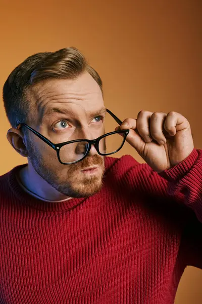 Handsome man in a red sweater holding a pair of stylish glasses. — Stock Photo