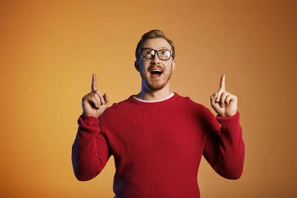 Handsome man in a red sweater pointing up. — Stock Photo