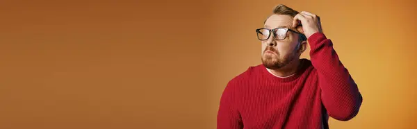 A man in a red sweater holds his head in deep thought. — Stock Photo