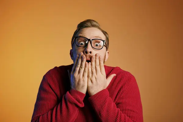 A stylish man in glasses covers his mouth with his hands. — Stock Photo