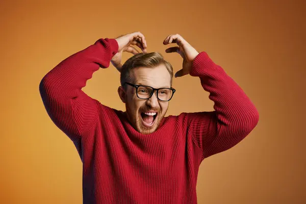 Un uomo con un maglione rosso che tiene la testa in pericolo. — Foto stock