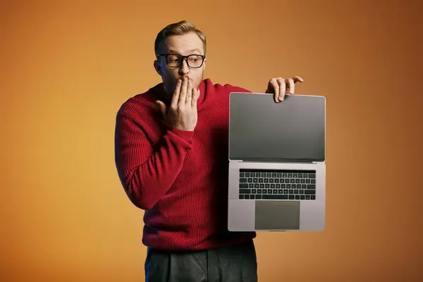 A handsome man in a red sweater holds a laptop. — Stock Photo