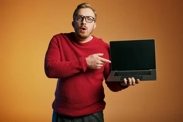 A dapper man in a red sweater confidently holds a laptop. — Stock Photo
