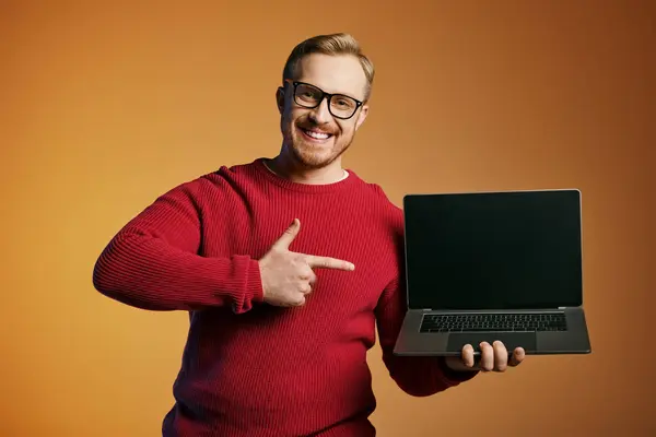 A man in a red sweater energetically holds a laptop. — Stock Photo