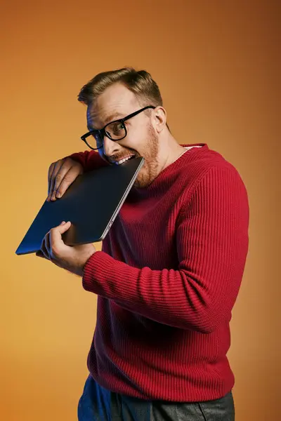 A stylish man in a red sweater confidently holds a laptop. — Stock Photo