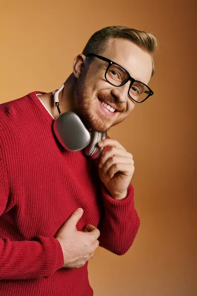 Stylish man in red sweater energetically holds headphones. — Stock Photo
