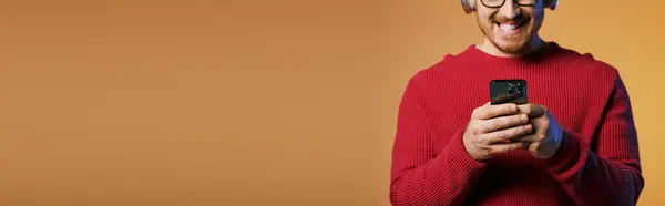 Handsome man in red sweater confidently holding a cell phone. — Stock Photo