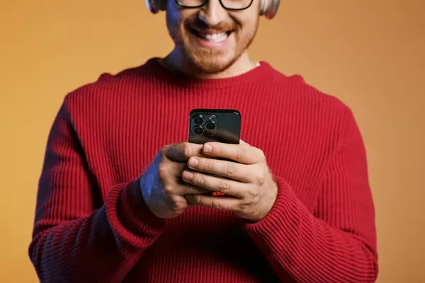 Stylish man in headphones captivated by cell phone screen. — Stock Photo
