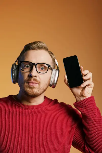 Stylish man in headphones holding cellphone, immersed in music. — Stock Photo