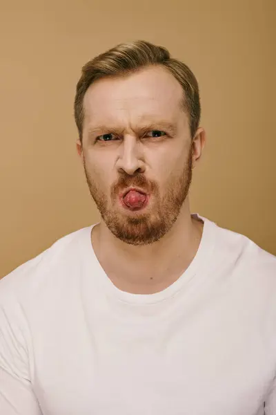 Handsome man in stylish attire making a silly face by sticking out his tongue. — Stock Photo