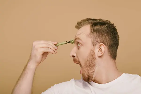 Um homem casualmente vestido energeticamente usando rolo de rosto. — Fotografia de Stock