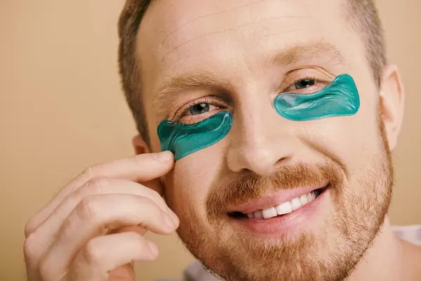 Un hombre con confianza con parches de ojos azules para una rutina de cuidado de la piel. - foto de stock