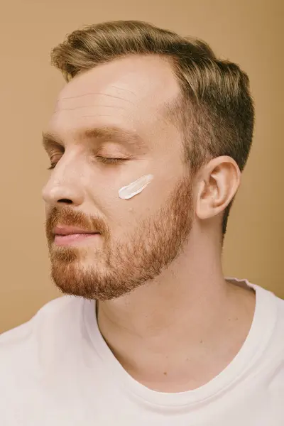 A stylish man wearing a facial cream relaxes during his skincare routine. — Stock Photo